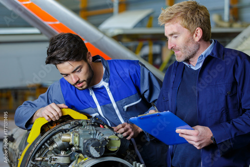 supervisor observing trainee engineer in airport hangar