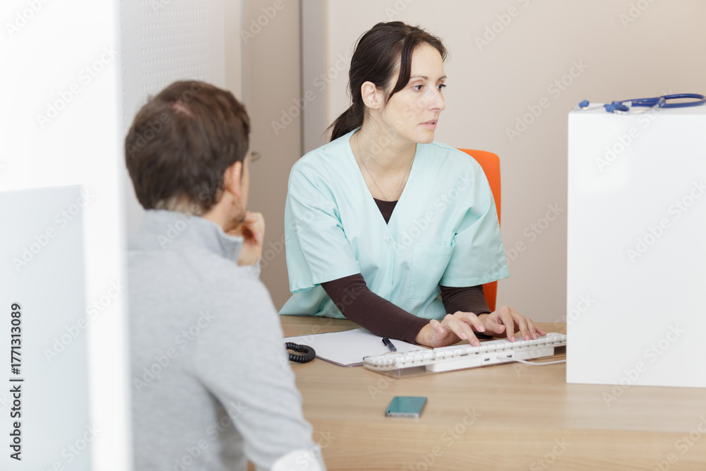 Obraz premium nurse and patient conversing at reception desk in hospital