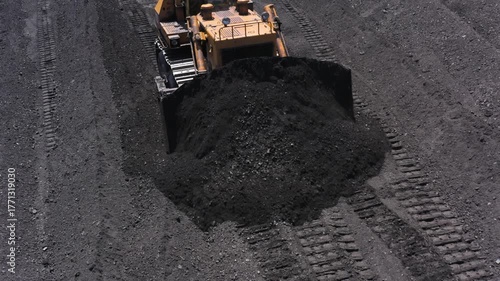 Aerial view of bulldozers transporting coal to conveyor belts at a thermal power plant during daytime operations