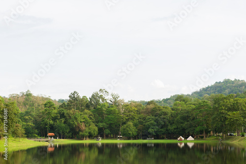 Large, well-maintained green lawn and open space bordered by dense tropical forest trees at Namtok Sam Lan National Park, Saraburi, Thailand.