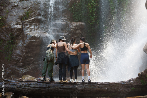 Carta da parati Group of women enjoying waterfall view on log