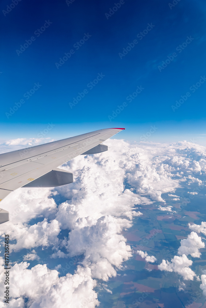 Fototapeta premium View from the airplane window at a beautiful cloudy sky and the airplane wing