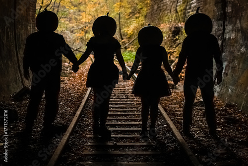 Friends wearing pumpkin heads hold hands in a spooky tunnel during autumn, creating a mysterious and playful atmosphere