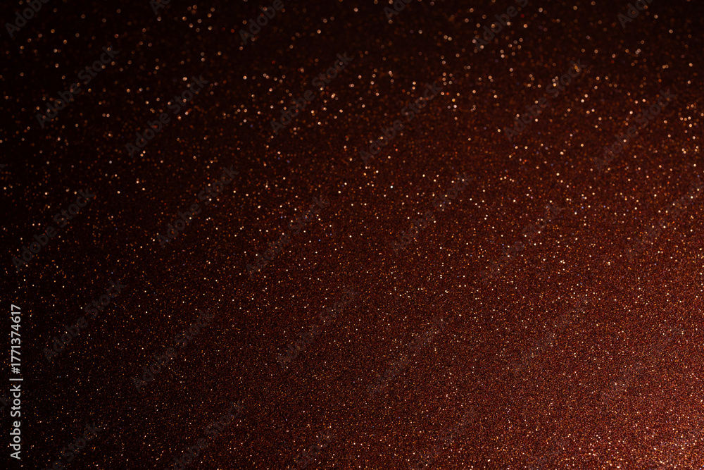Obraz premium Red brown glitter background with shadowed edges and bright spot in lower left, sparkling grains spread outward creating radiant shimmering abstract composition