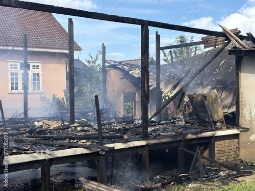 A burnt-down house reduced to its skeletal frame after a devastating fire. Charred beams and blackened walls stand as silent remnants of destruction