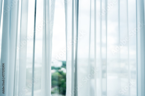 Elegant white sheer curtains allow soft sunlight to filter into a serene room, creating a bright and peaceful home interior atmosphere.