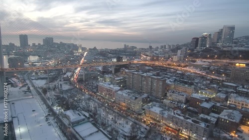 Wallpaper Mural View of evening traffic in snow-covered Vladivostok. Cars are stuck in a traffic jam, slowly moving along the city roads as the city gradually transitions into dusk. Timelapse Torontodigital.ca