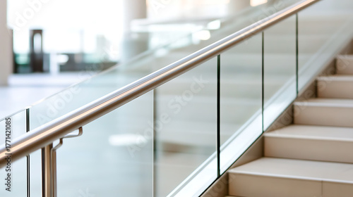 Fototapeta Naklejka Na Ścianę i Meble -  A modern staircase with stainless steel handrail and glass panels creates a bright and open space for movement between floors within a commercial building. Minimalist design.