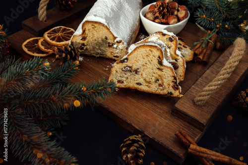 Christmas stollen on a wooden board with green branches of a Christmas tree. Christmas background, Christmas desserts