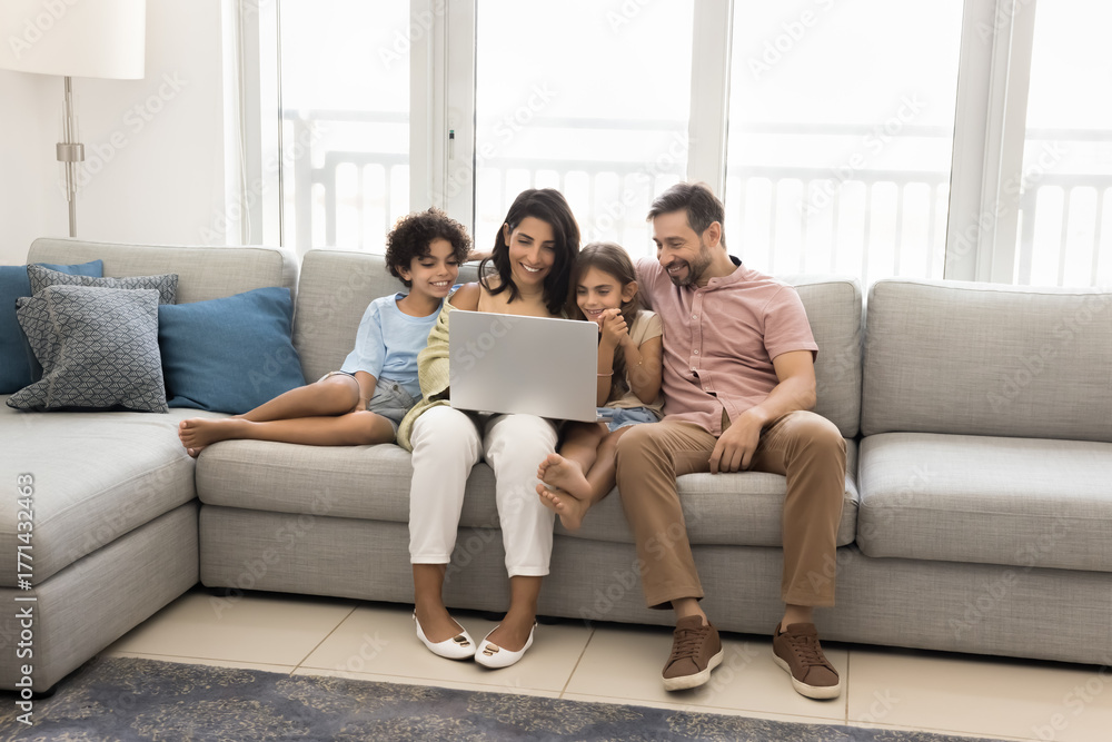 Obraz premium Modern family of four spending time together with laptop