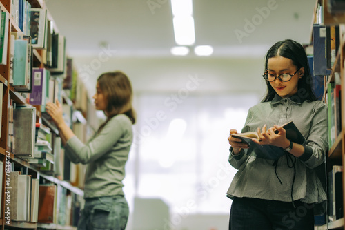 Canvas Print Woman finding academic book in university library, depicting education, research skills, and pursuit of lifelong learning
