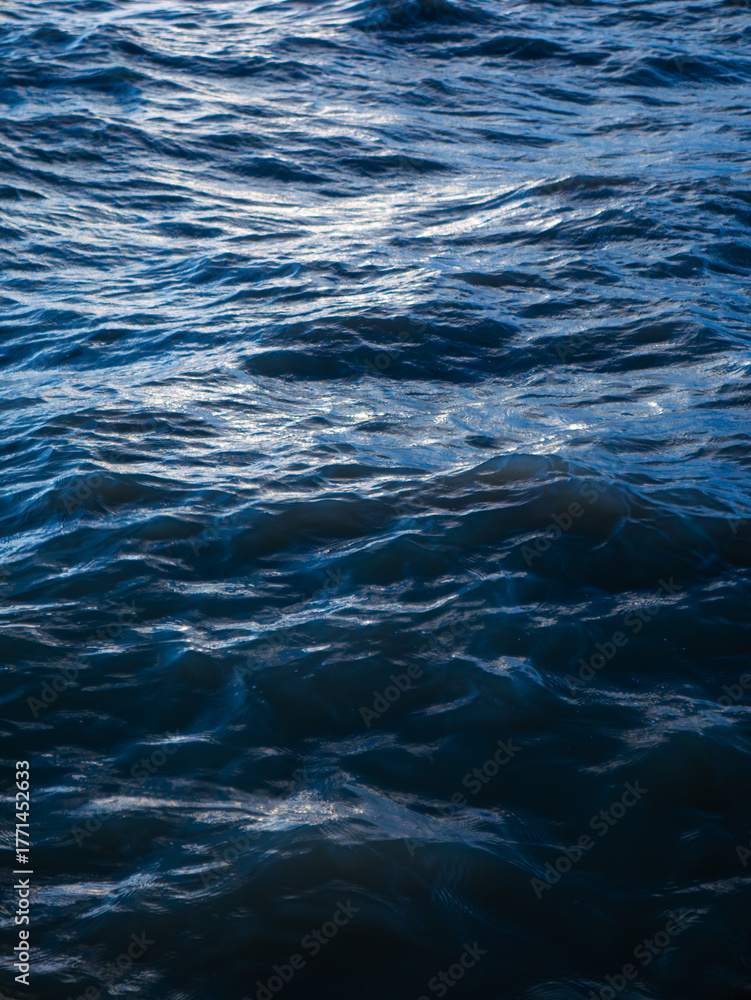 Naklejka premium Deep Blue Ocean Water Waves Surface with Silver Light Reflection - Abstract Sea Texture Background Pattern
