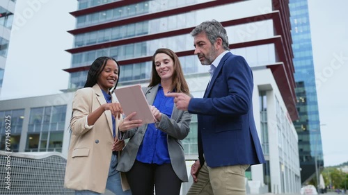 Diverse business team meeting outdoors with a tablet