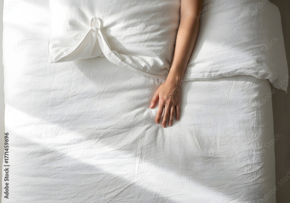 Naklejka premium Relaxing hand on white bed linen minimalist aesthetic