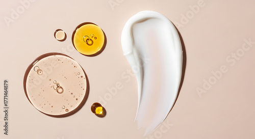 Close up of cosmetic textures with oil droplets and a creamy swirl on a neutral background