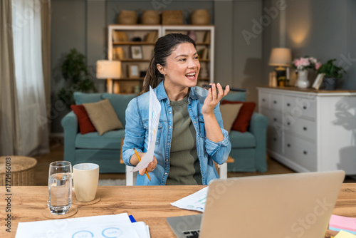 Foto Freelance businesswoman in home office reviewing charts and dictating a voice no