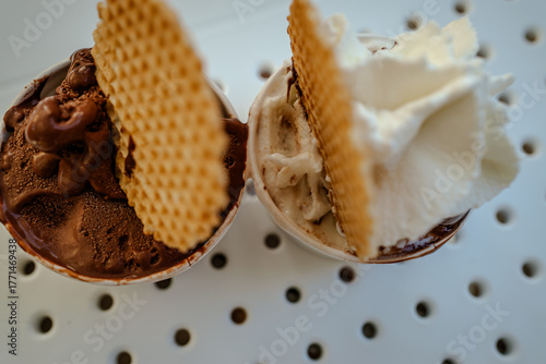 The photo of Italian vanilla and chocolate gelato in the street cafe, traditional ice cream with waffle decor. Summer atmosphere, daylight, travel to Italy
