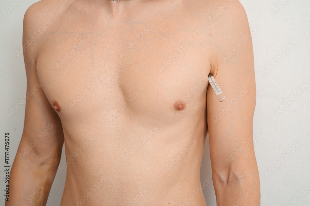 Fototapeta premium Man checking body temperature with thermometer under armpit