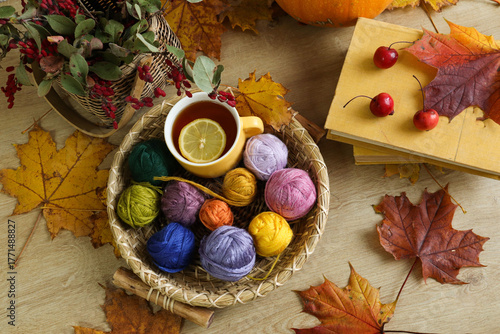 Autumn craft: colorful skeins of yarn with books and a cup of tea, top view