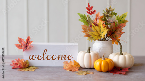 Autumn welcome arrangement with pumpkins, dried flowers, and a wooden welcome sign on a rustic wooden table.
