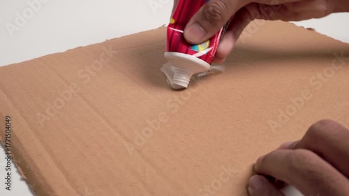 Close up of hands applying rat glue to cardboard, ready for pest control and rodent trapping.