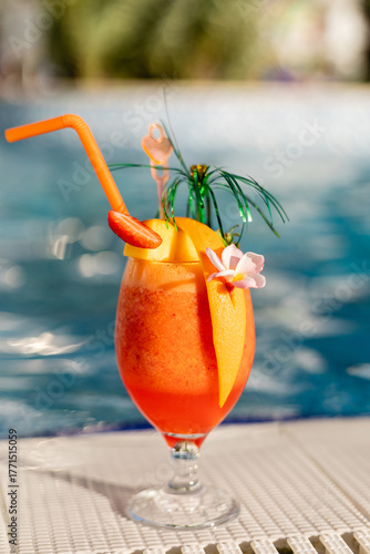Canvastavla A vibrant orange cocktail sits beside a refreshing pool, adorned with fruit slices and colorful decorations
