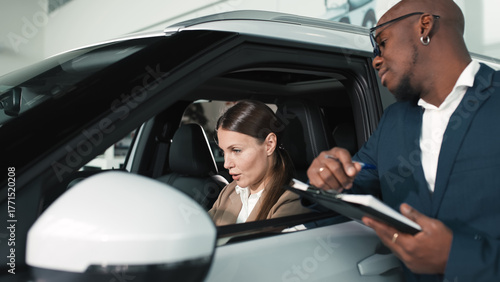 Εκτύπωση καμβά African American man in a suit presenting car features to a Caucasian woman insi