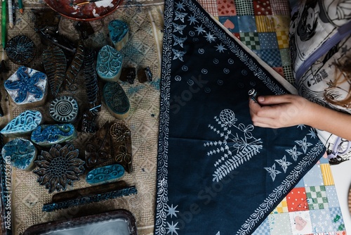 Batik and hand-woven textiles: children's hands apply patterns to fabric, alongside carved stamps with ornaments. Creativity, handmade, and ethnic design.