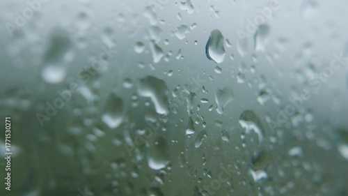 Transparent droplets sliding on foggy window while rain falls outside creating relaxing cinematic view. Abstract mood.