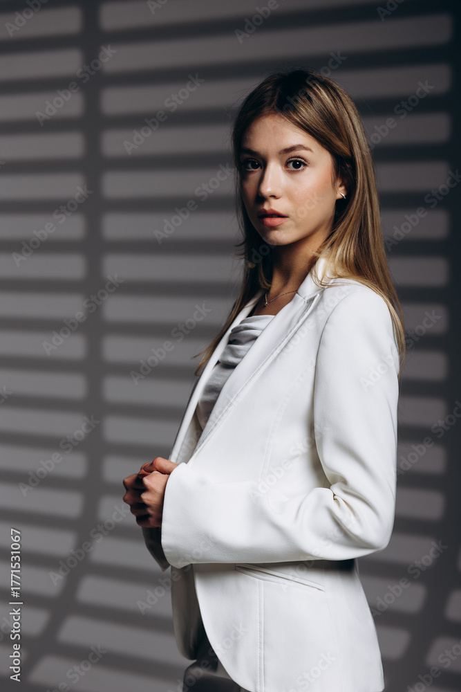 Fototapeta premium Young business woman wearing white suit standing isolated on grey background