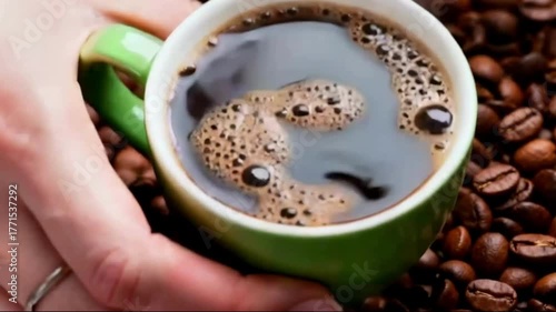 Pouring Hot Coffee into Ceramic Cup with Rising Steam. A close-up view of a hand holding a white ceramic cup while hot coffee is being poured, creating ripples on the surface. 