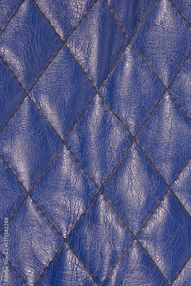 Obraz premium A detailed vertical close-up of a dark navy blue, textured faux leather surface featuring a continuous diamond-shaped quilted stitching pattern, suitable for a background