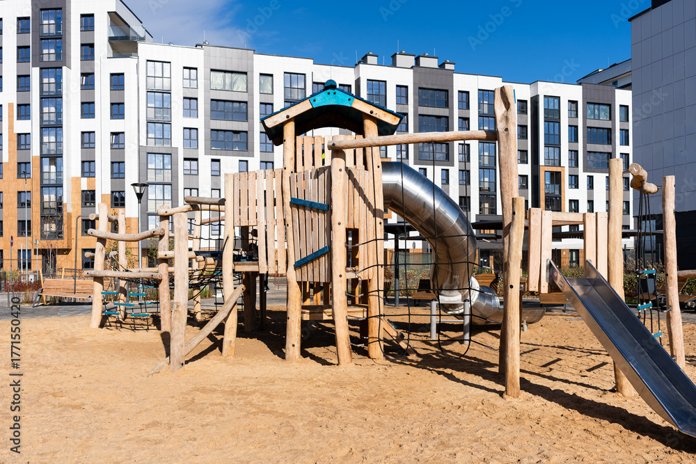 Fototapeta premium Children's wooden playground with slide and climbing frame in urban setting 