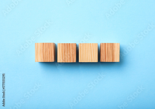 Wooden cubes on light blue background, top view