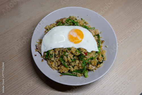 A plate of spicy fried rice with fried egg on top.