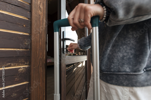 A woman's hands holding a suitcase open a door with a key. Concept of travel, business trips, or relocation.