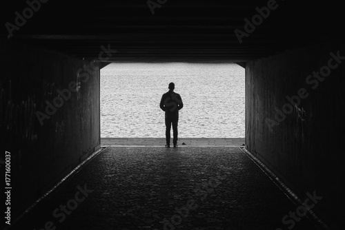 Man looking at water from tunnel