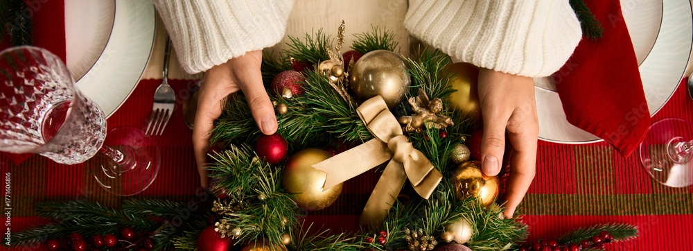 Obraz premium Creating a festive Christmas wreath with shiny ornaments and holiday spirit at the dining table