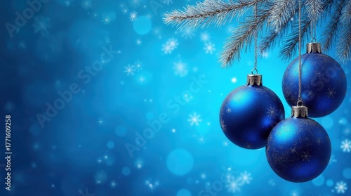 Blue Christmas ornaments hanging from a frosted pine branch. Festive winter holiday background with snowflakes and copy space