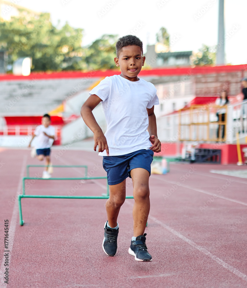 Fototapeta premium Young children having athletic exercise class running on the track, healthy lifestyle and children sport education concepts
