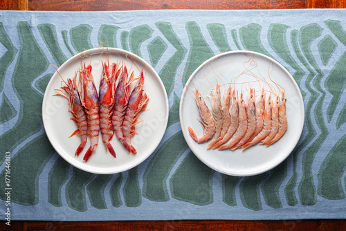 Top view of fresh raw shrimp on plates with blue abstract background