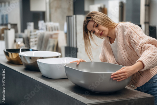Young Woman Examining Stylish Bathroom Sinks in Home Improvement Store