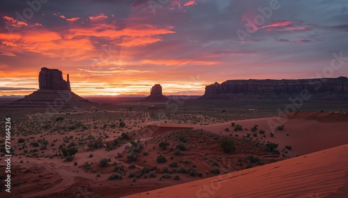 Fototapeta Naklejka Na Ścianę i Meble -  Crimson Sky Over Eroded Formations Sand Dunes and Sculpted Rocks Landscape.
