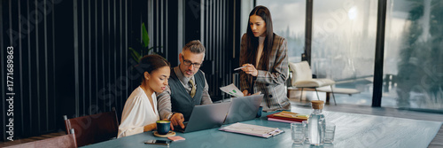 A team of professionals is working on a major project in a modern office with a beautiful city view