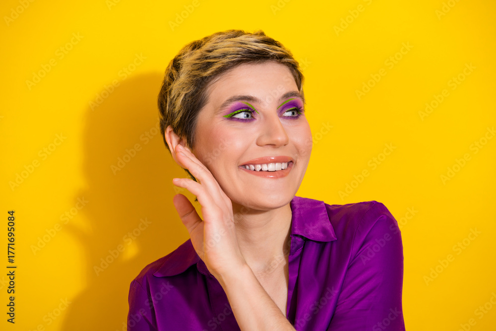 Fototapeta premium Young glamorous woman with short blonde hair in a purple blouse smiles against a bright yellow background