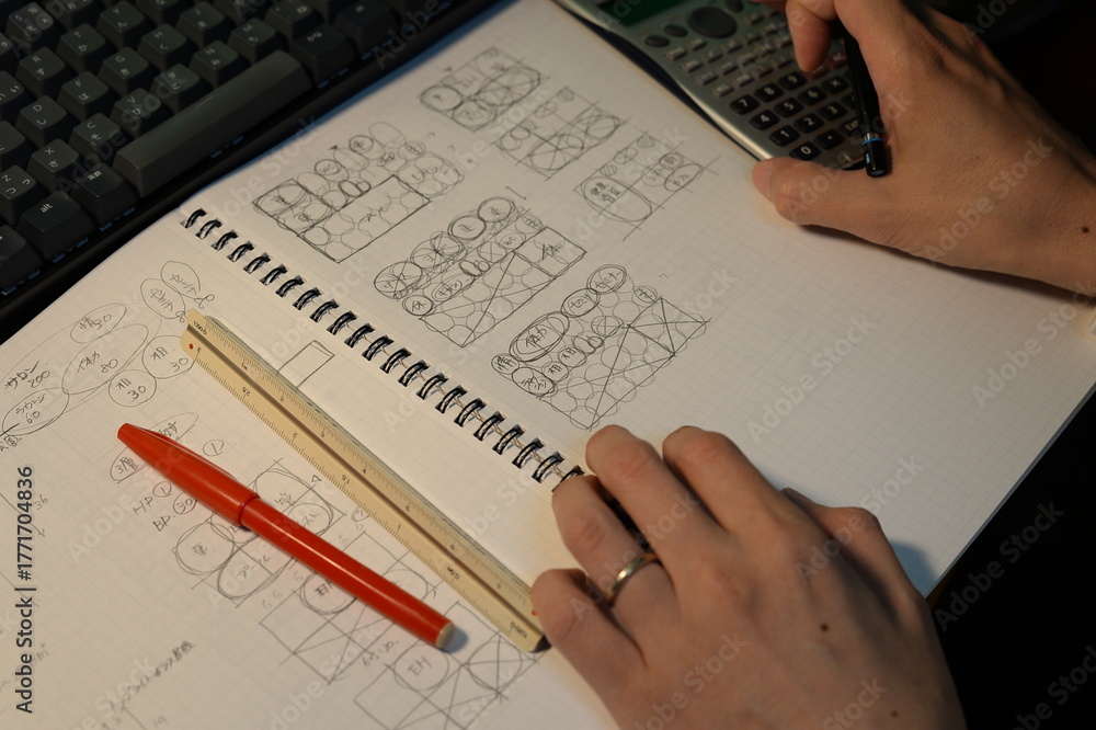 Obraz premium 夜にプランを検討する建築士の手元 The hands of an architect reviewing plans at night