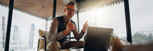 Foto A cheerful businessman happily communicates through his laptop in a modern and s