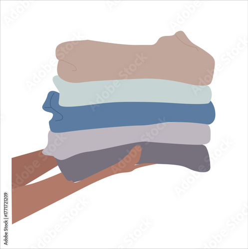 Hand holds a stack of folded donation clothes. hands holding folded clothes