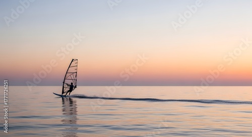 Minimal windsurfer gliding across open sea under soft morning sky and subtle waves