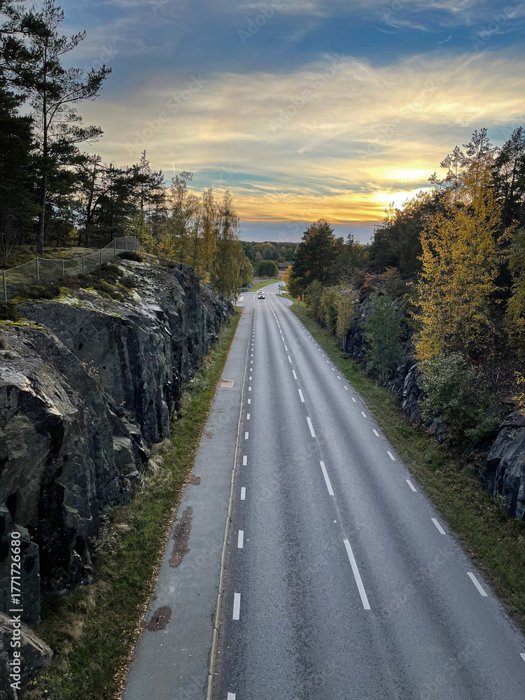 Obraz premium The road between the rocks stretches into the distance towards the setting sun